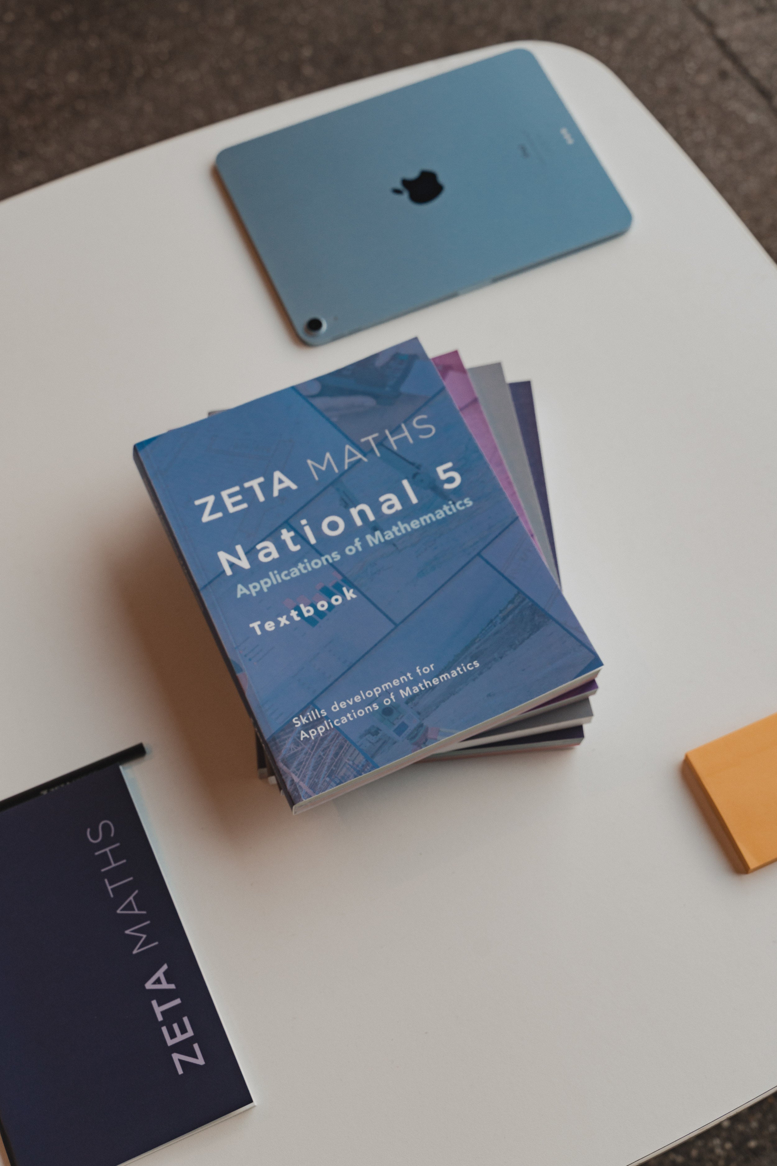 Zeta Maths National 5 textbooks on a white surface with a smartphone in the background.