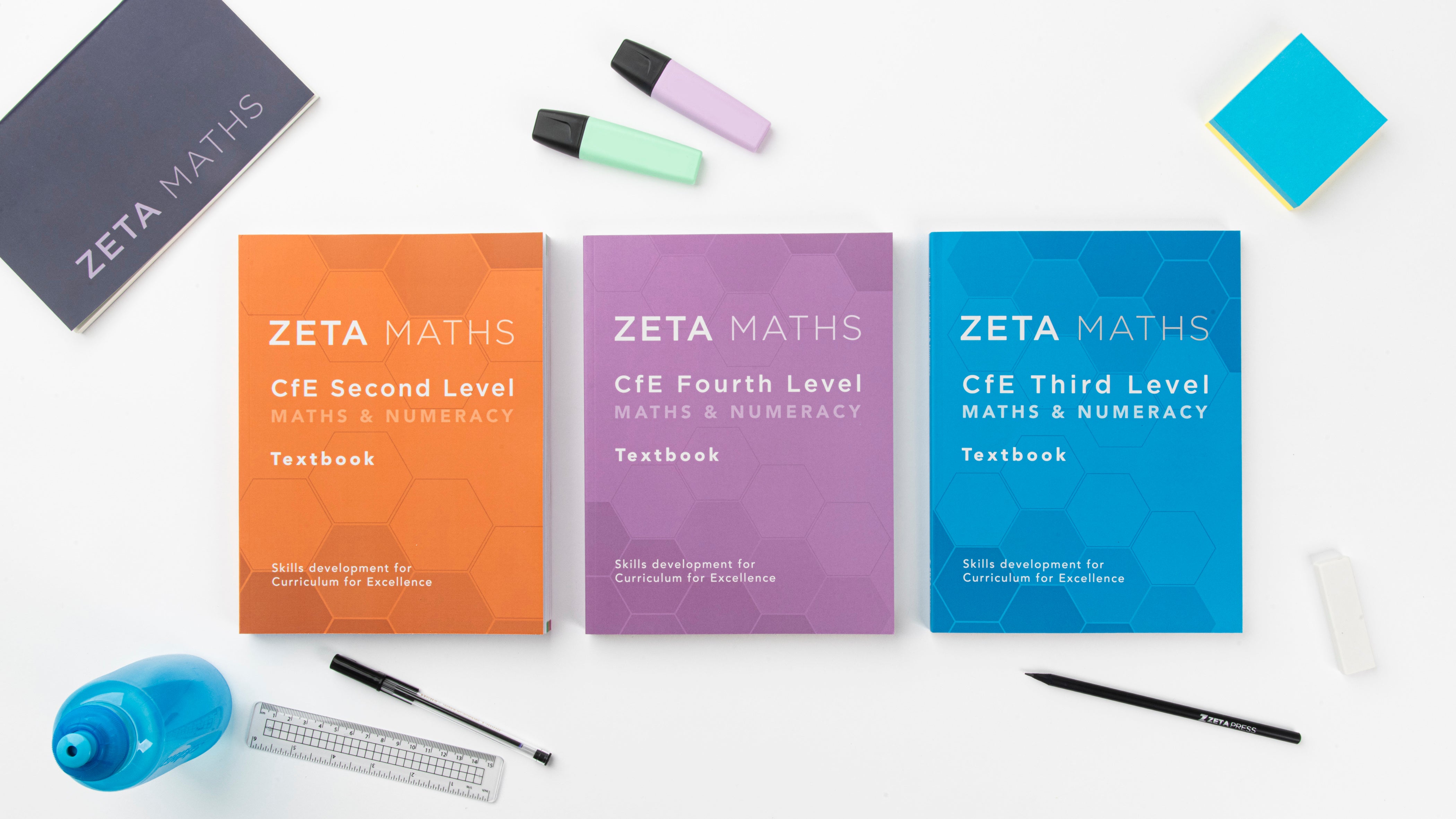 Three ZETA books and notepad with stationary on a white background.